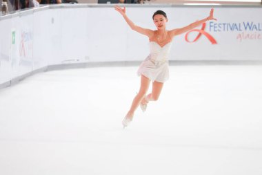 Mavi elbiseli yetenekli artistik patinajcı zarif bir şekilde karmaşık bir duruş sergiliyor.