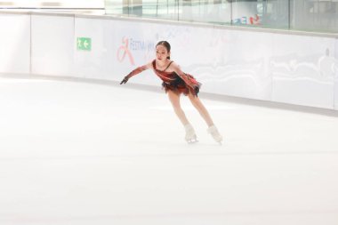 Mavi elbiseli yetenekli artistik patinajcı zarif bir şekilde karmaşık bir duruş sergiliyor.