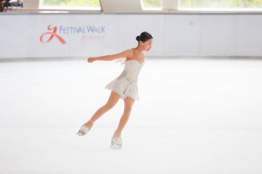 Mavi elbiseli yetenekli artistik patinajcı zarif bir şekilde karmaşık bir duruş sergiliyor.