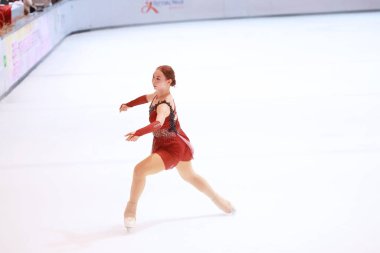 Mavi elbiseli yetenekli artistik patinajcı zarif bir şekilde karmaşık bir duruş sergiliyor.