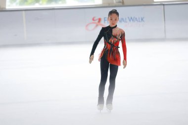 Mavi elbiseli yetenekli artistik patinajcı zarif bir şekilde karmaşık bir duruş sergiliyor.