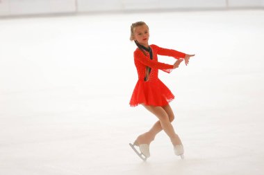 Mavi elbiseli yetenekli artistik patinajcı zarif bir şekilde karmaşık bir duruş sergiliyor.