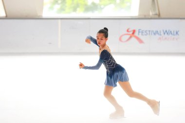 Mavi elbiseli yetenekli artistik patinajcı zarif bir şekilde karmaşık bir duruş sergiliyor.