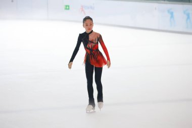 Mavi elbiseli yetenekli artistik patinajcı zarif bir şekilde karmaşık bir duruş sergiliyor.