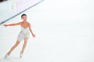 Mavi elbiseli yetenekli artistik patinajcı zarif bir şekilde karmaşık bir duruş sergiliyor.