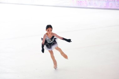 Mavi elbiseli yetenekli artistik patinajcı zarif bir şekilde karmaşık bir duruş sergiliyor.