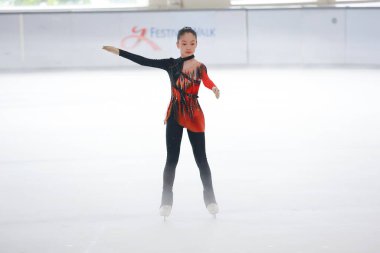 Mavi elbiseli yetenekli artistik patinajcı zarif bir şekilde karmaşık bir duruş sergiliyor.