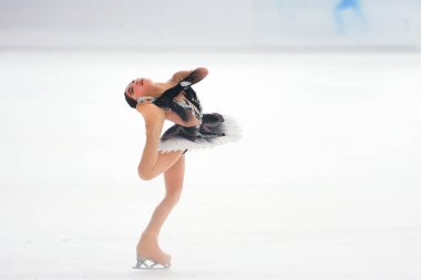 Mavi elbiseli yetenekli artistik patinajcı zarif bir şekilde karmaşık bir duruş sergiliyor.