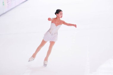 Mavi elbiseli yetenekli artistik patinajcı zarif bir şekilde karmaşık bir duruş sergiliyor.