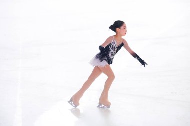 Mavi elbiseli yetenekli artistik patinajcı zarif bir şekilde karmaşık bir duruş sergiliyor.