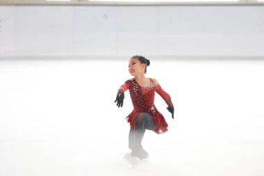 Mavi elbiseli yetenekli artistik patinajcı zarif bir şekilde karmaşık bir duruş sergiliyor.