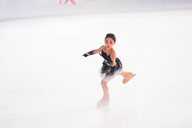 Mavi elbiseli yetenekli artistik patinajcı zarif bir şekilde karmaşık bir duruş sergiliyor.