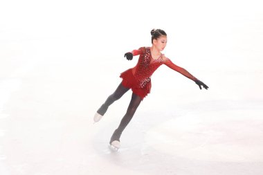 Mavi elbiseli yetenekli artistik patinajcı zarif bir şekilde karmaşık bir duruş sergiliyor.