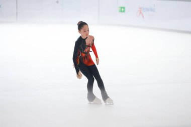 Mavi elbiseli yetenekli artistik patinajcı zarif bir şekilde karmaşık bir duruş sergiliyor.