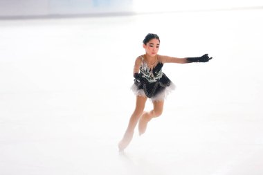 Mavi elbiseli yetenekli artistik patinajcı zarif bir şekilde karmaşık bir duruş sergiliyor.