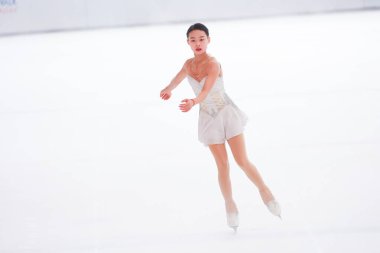 Mavi elbiseli yetenekli artistik patinajcı zarif bir şekilde karmaşık bir duruş sergiliyor.