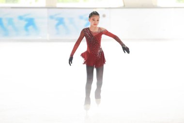 Mavi elbiseli yetenekli artistik patinajcı zarif bir şekilde karmaşık bir duruş sergiliyor.