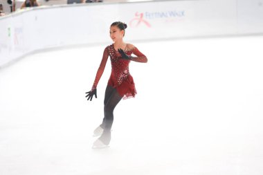 Mavi elbiseli yetenekli artistik patinajcı zarif bir şekilde karmaşık bir duruş sergiliyor.