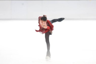 Mavi elbiseli yetenekli artistik patinajcı zarif bir şekilde karmaşık bir duruş sergiliyor.