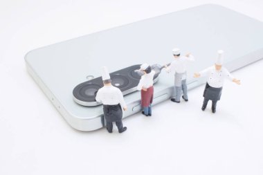 Küçük şef figürleri şık bir akıllı telefonun etrafında toplanıyor.