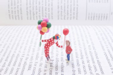 Renkli bir palyaço oyuncağının balonla oynadığı tuhaf bir minyatür sahne.