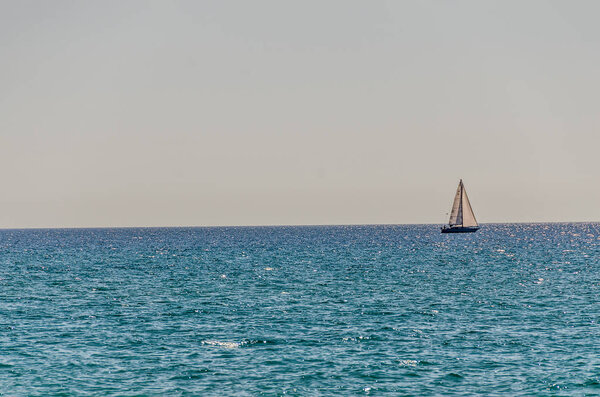 Sunlit sailboat on Lake Michigan with a clear sky and shades of blue in the water