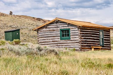 Tepede oturan bir müştemilatı olan kütük kabini.