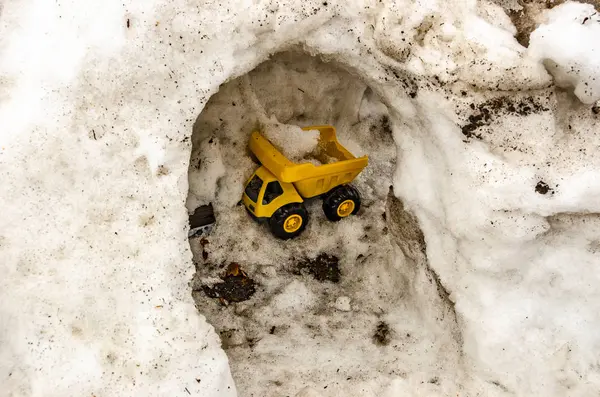 Gula leksaksbilen släpar snö — Stockfoto
