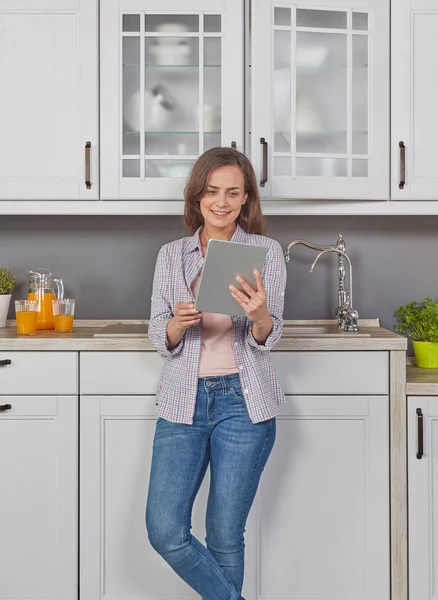 Woman in kitchen with digital tablet