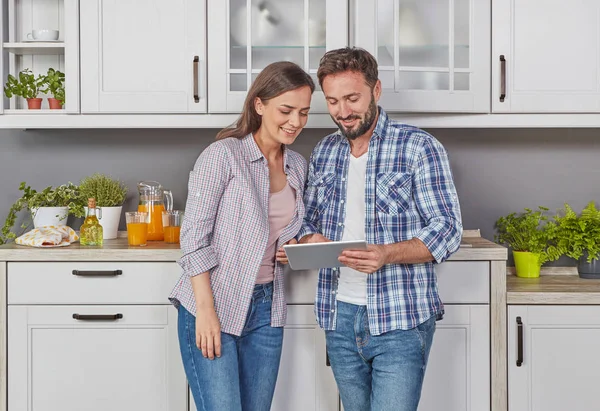 Young couple in the kitchen with digital tablet