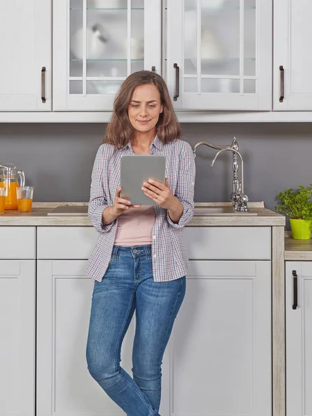 Woman in kitchen with digital tablet