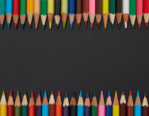 Multi-colored pencils frame on blackboard