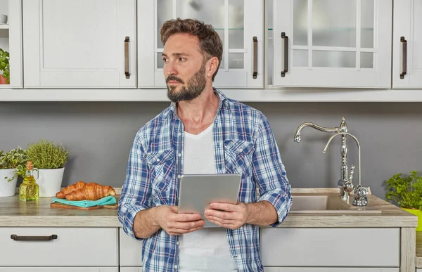 Man in kitchen with digital tablet
