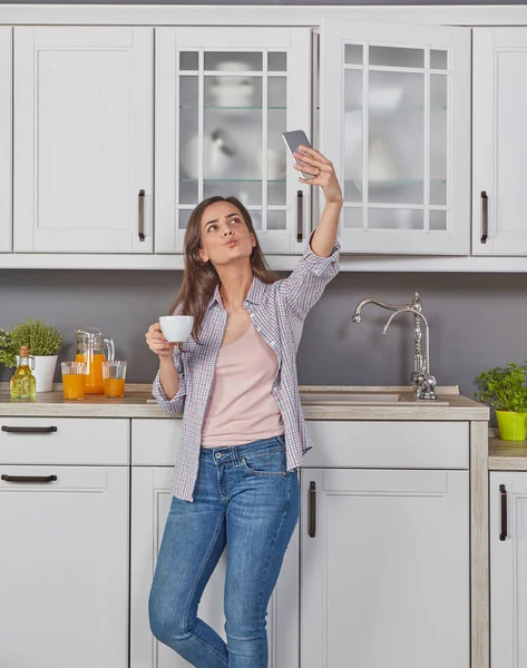 Genç kadın mutfakta bir selfie alarak cep telefonunuzla