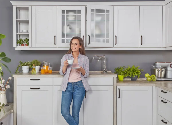 Genç bayan mutfakta kahve içiyor.