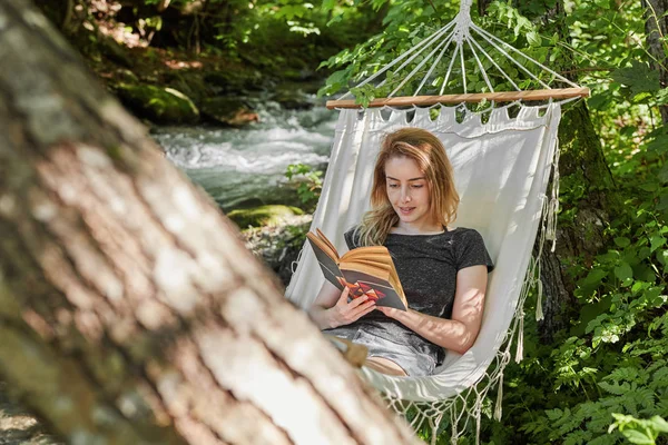 Vrolijke vrouw lezen in een hangmat — Stockfoto