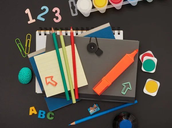 Overhead shot of stationery on wood desk with paper notepad and frame of school office supplies