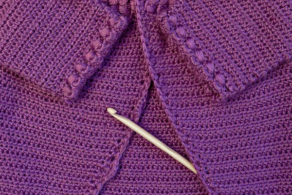 Baby purple cardigan, crocheted close-up and wooden hook