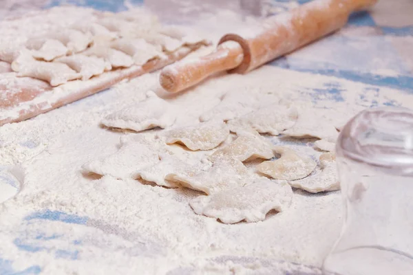 Dumplings with rolling pin on table sprinkled with flour