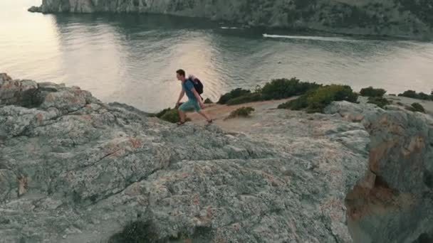 Mann klettert auf Felsen und hebt die Hände — Stockvideo