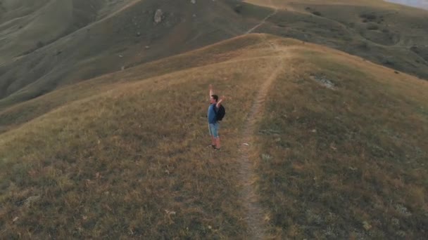 Man die op de top van een berg met opgeheven handen — Stockvideo