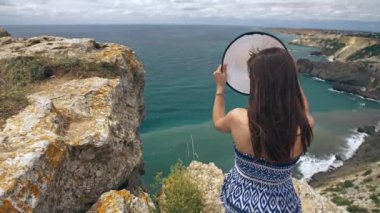 Kayanın üzerinde oturan ve deniz manzarası izlerken kadın