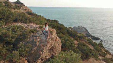 Kadın rock ve izle deniz manzarası üzerinde oturur