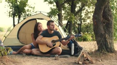 Genç çift ormandaki gitar çalmaya