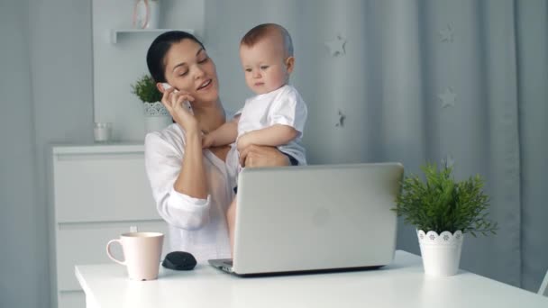 Jeune mère tenant bébé pendant qu'elle travaille au bureau à domicile — Video