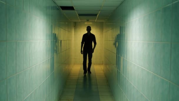 Um homem caminha por um corredor — Vídeo de Stock