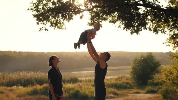 Familia joven con bebé al atardecer — Vídeos de Stock