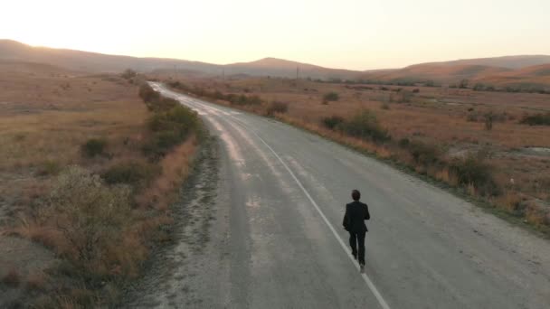 Человек в костюме бежит по пустой дороге — стоковое видео
