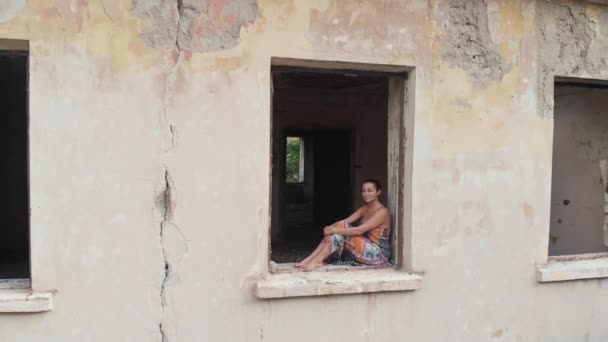 Mujer sentada en la ventana en casa abandonada — Vídeo de stock