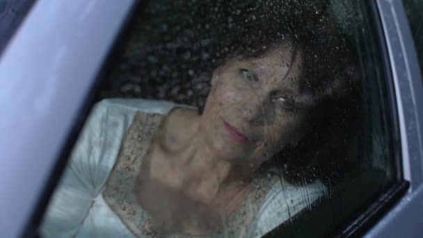 Жінка в машині дивиться на дощ — стокове відео